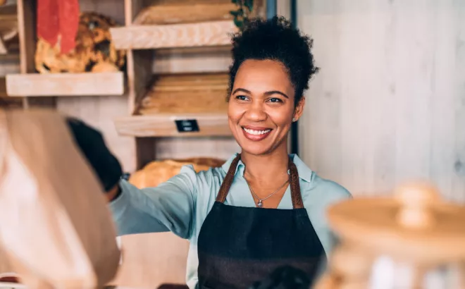 Een mevrouw met een glimlach overhandigt een bestelling