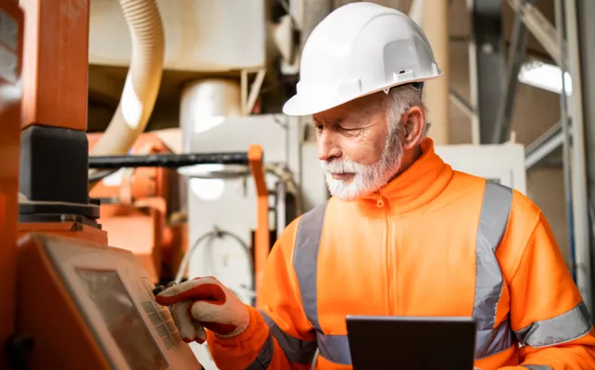 Arbeider met helm die een scherm aanraakt op de werkvloer