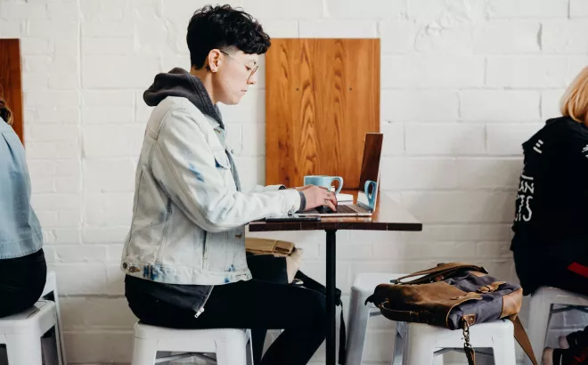 Een persoon typt op een laptop in een café