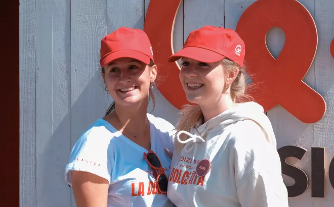 Twee jobstudenten van 15 jaar met een rode pet voor het logo van Q-Music