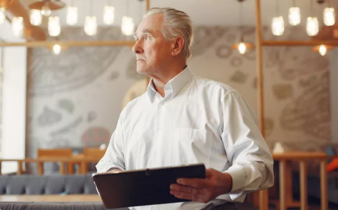 Un homme retraité en tenue de travail appuyant sur les boutons d'une machine.