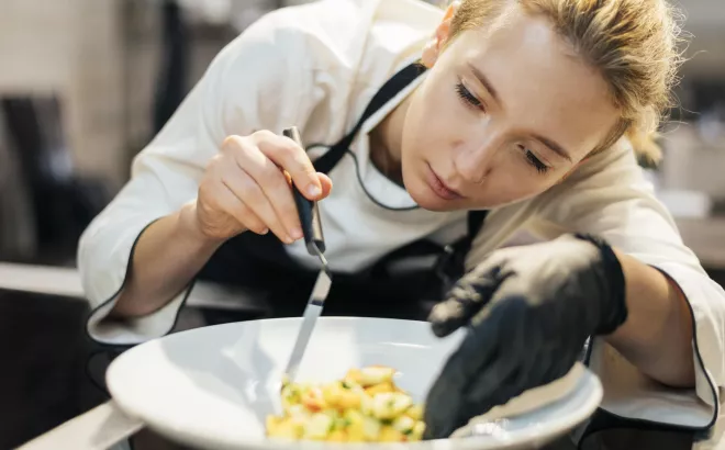 Une femme compose un plat dans une assiette