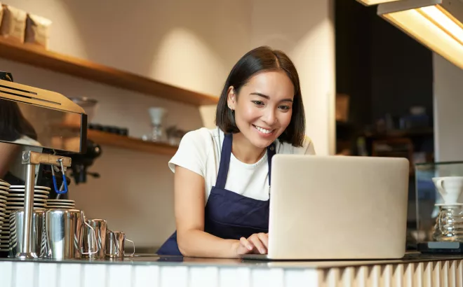 Une femme regarde son écran d'ordinateur portable en souriant
