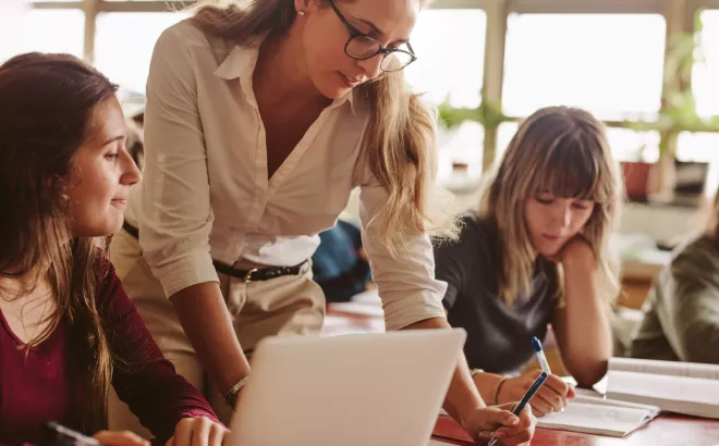 Leerkracht helpt haar leerlingen in de les