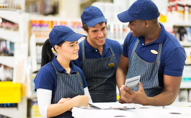 Drie bijverdieners kijken glimlachend naar een rekenmachine