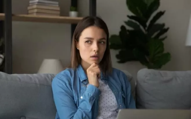 Une étudiante qui réfléchi devant son ordinateur portable