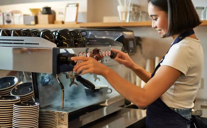 Une étudiante travaille comme barista et prépare un café